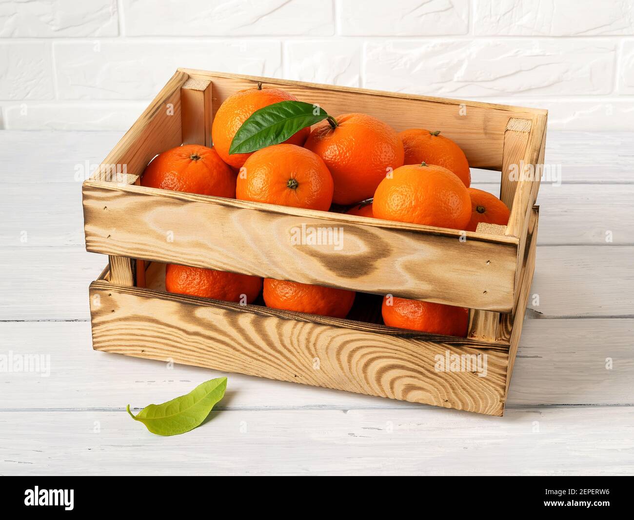 Caja de madera con mandarinas de color naranja dulce en una mesa de cocina.  Cítricos frescos en caja de madera. Envases ecológicos de estilo rústico  para frutas y veggi Fotografía de stock -