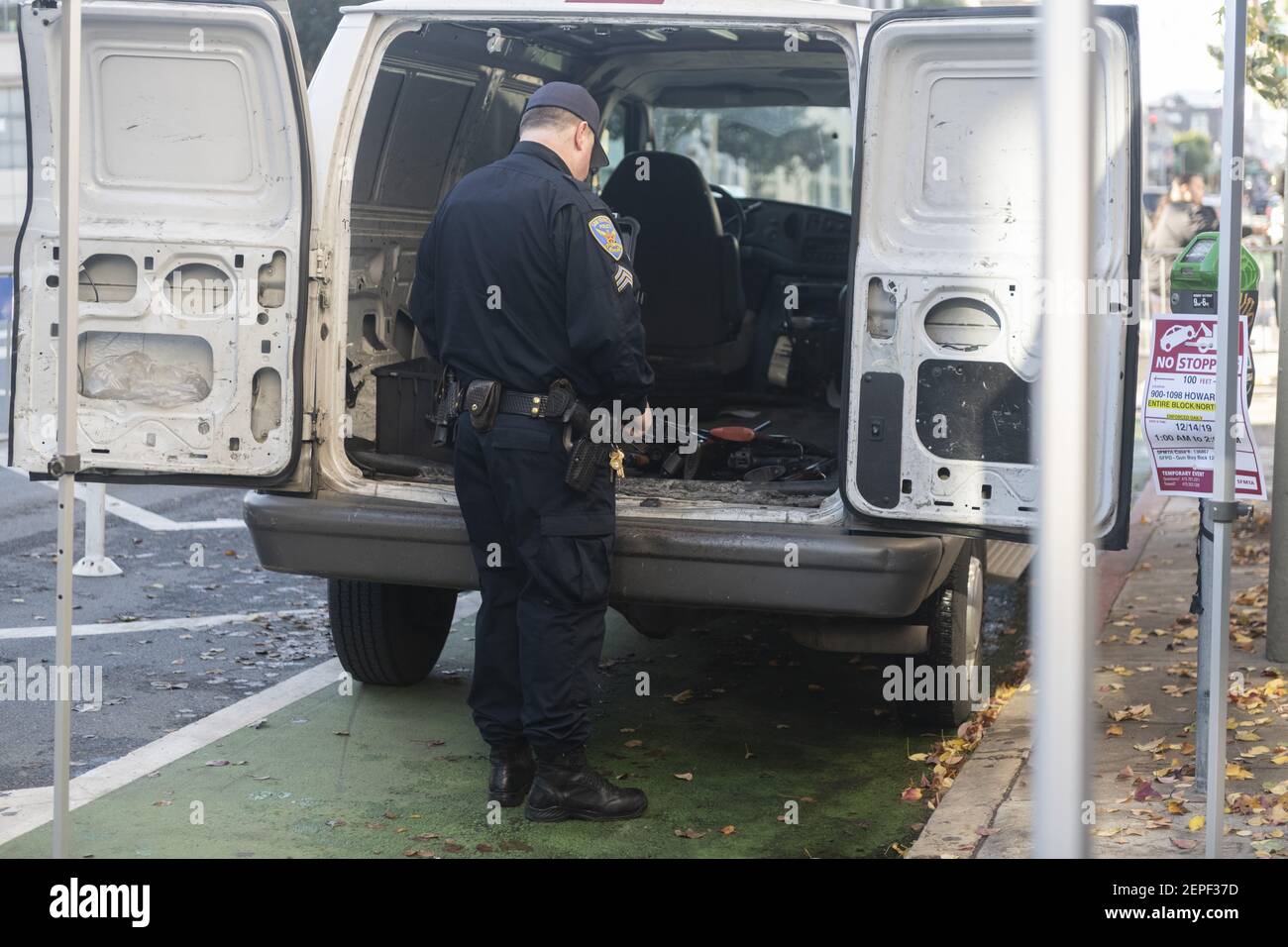 Un oficial de policía de San Francisco mira la pila de armas comercian con  personas anual durante el programa de compra de armas con el evento es  visto en la parte trasera