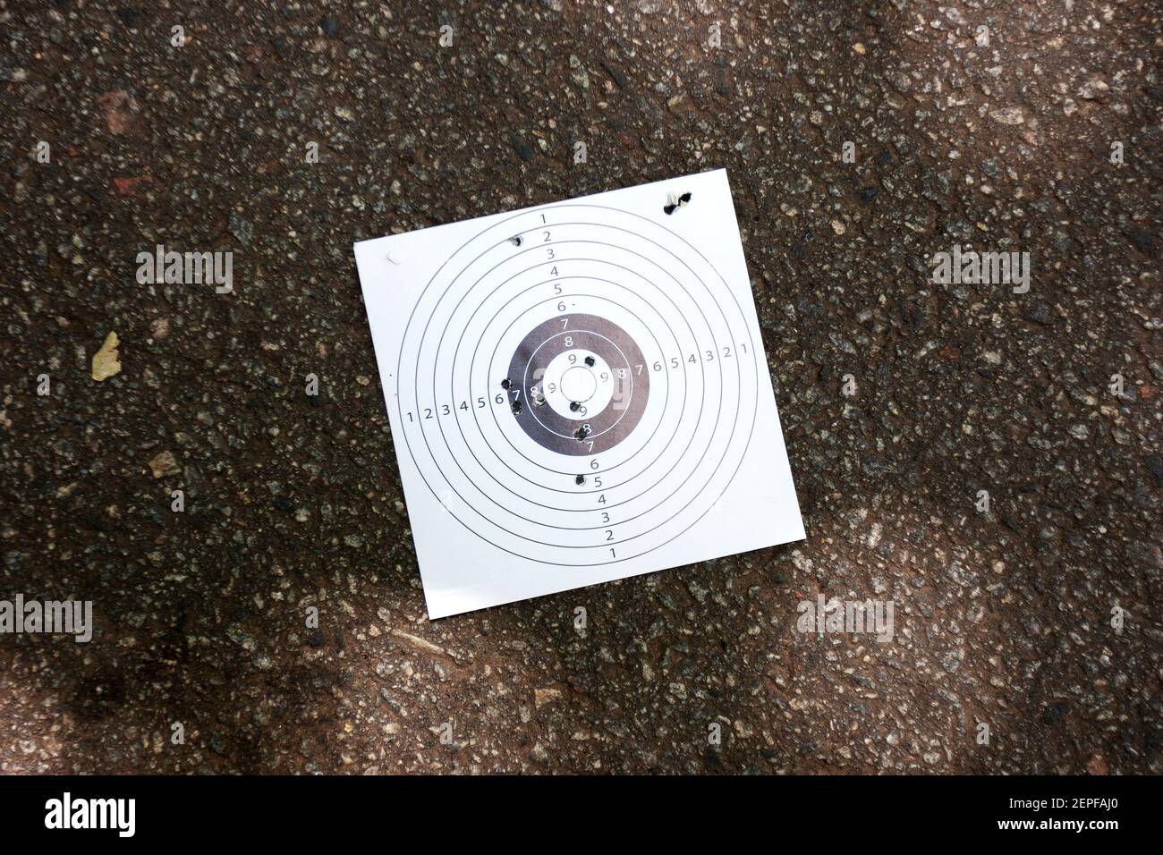objetivo de papel usado con agujeros de bala en el fondo de asfalto urbano. concepto de dilación y ataque Foto de stock