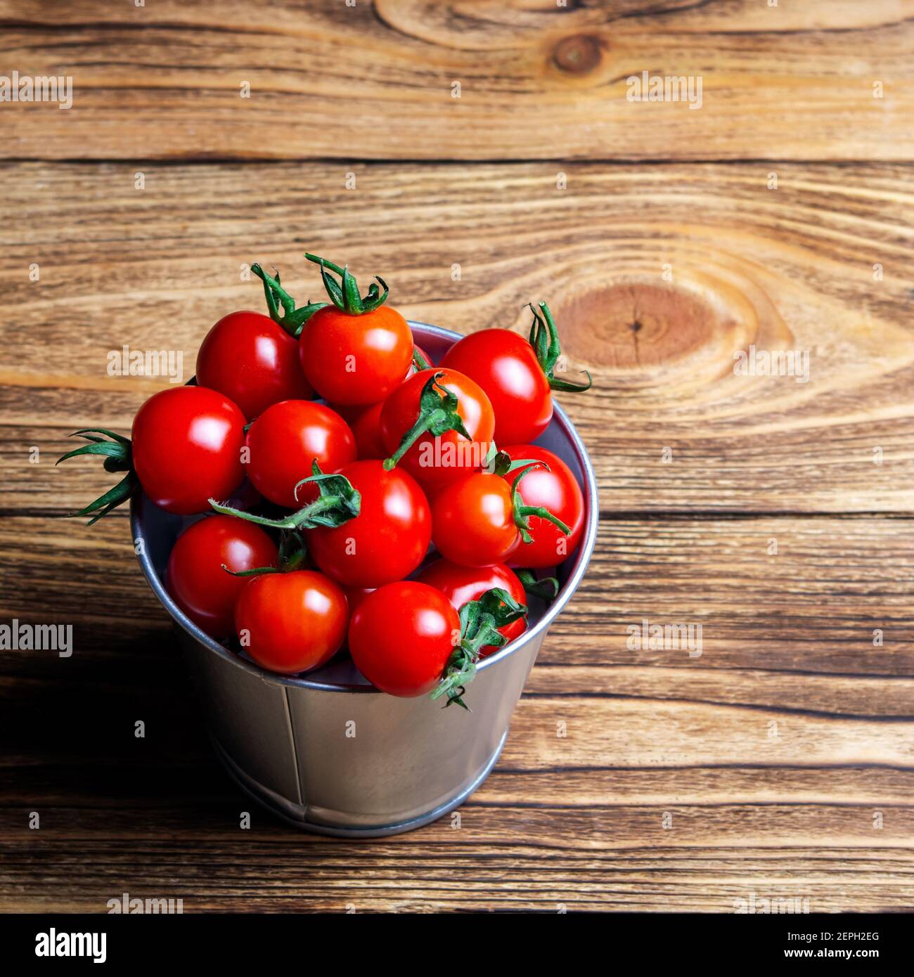 pequeño cubo de tomates cherry rojos frescos sobre una mesa de madera. Vista superior. Cosecha. Espacio natural de la comida Foto de stock