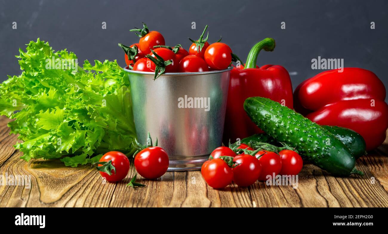 Conjunto de verduras para ensalada, pepinos, pimientos, tomates cherry rojos frescos en una mesa de madera.Vista lateral. Cosecha. Alimentos naturales. Foto de stock