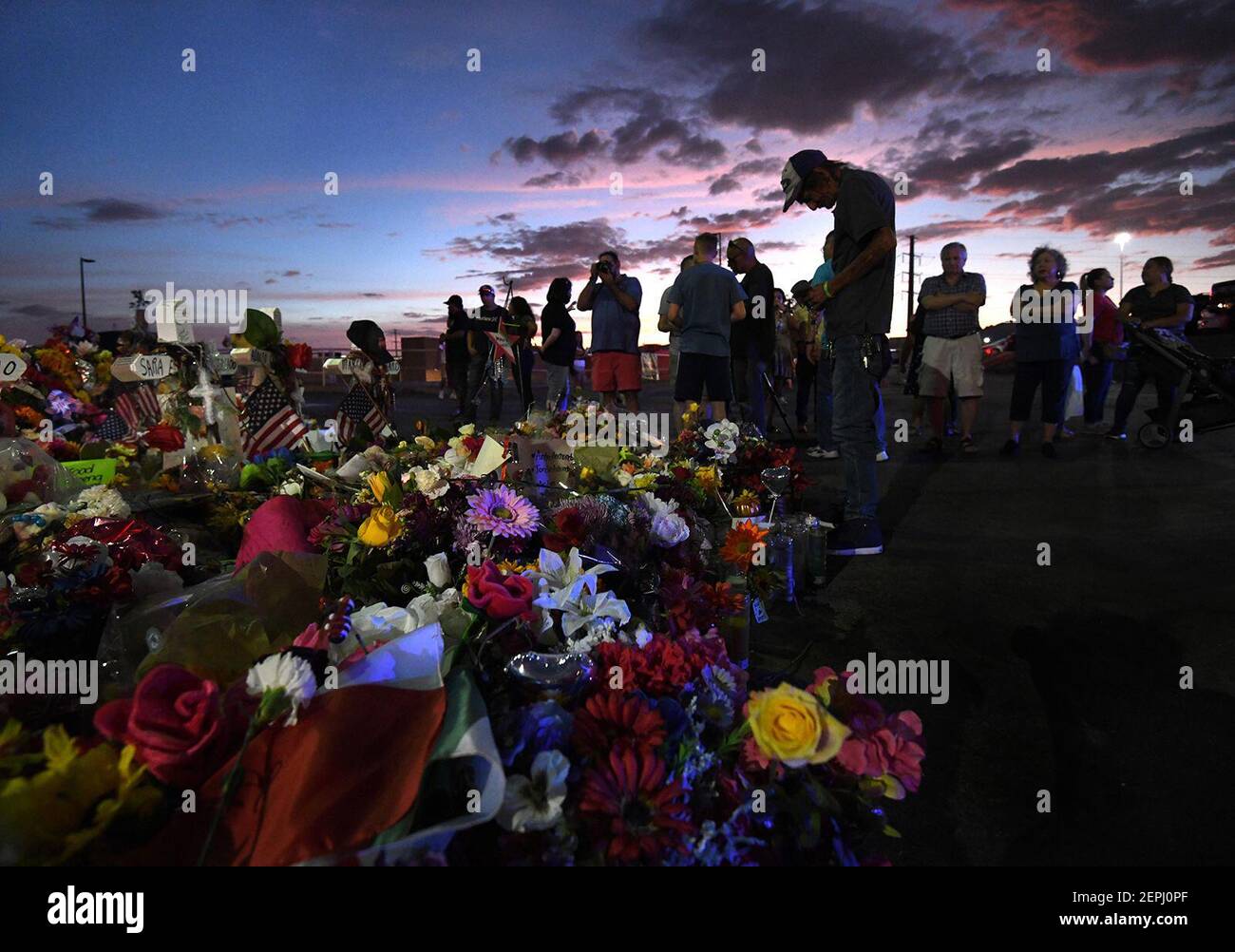 Antonio Basco permanece en silencio en la cruz de su esposa mientras los miembros de la familia visitan el sitio conmemorativo al anochecer después de los servicios funerarios para la víctima de disparos masivos de Walmart, Margie Reckard, el 17 de agosto de 2019 en el Paso, Texas. (Carol Guzy/Zuma Press/TNS) Foto de stock