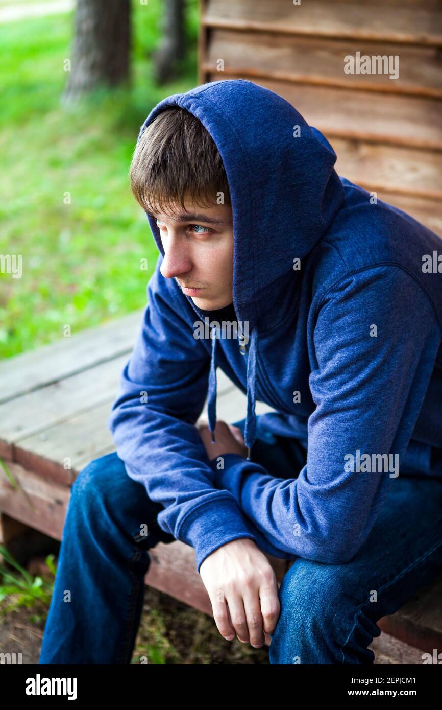 Triste joven hombre en una sudadera con capucha cerca de la casa al aire  libre Fotografía de stock - Alamy