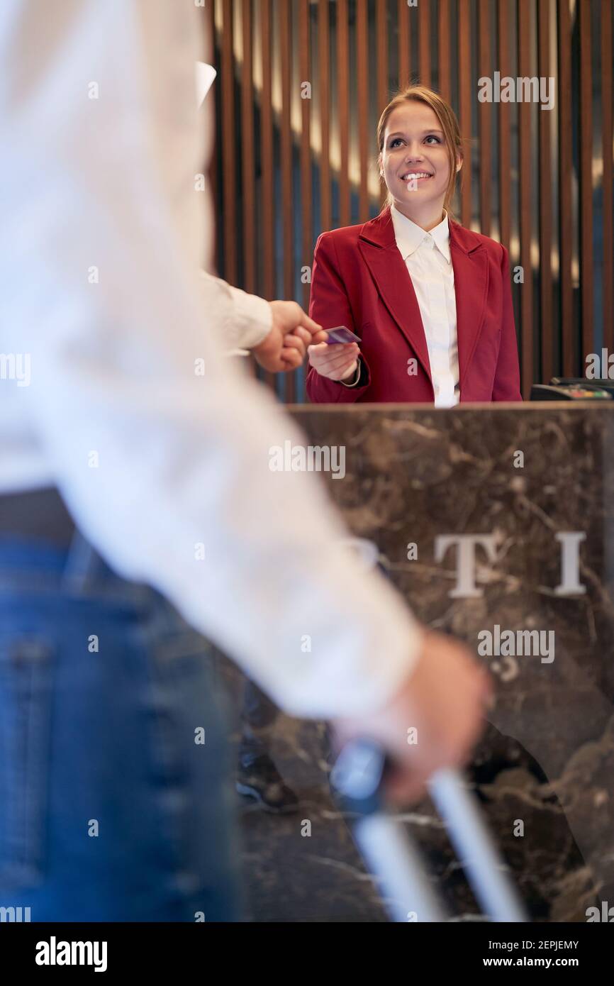 Una recepcionista agradable y encantadora que atiende a un huésped en el hotel. Turismo, negocios, hotel Foto de stock