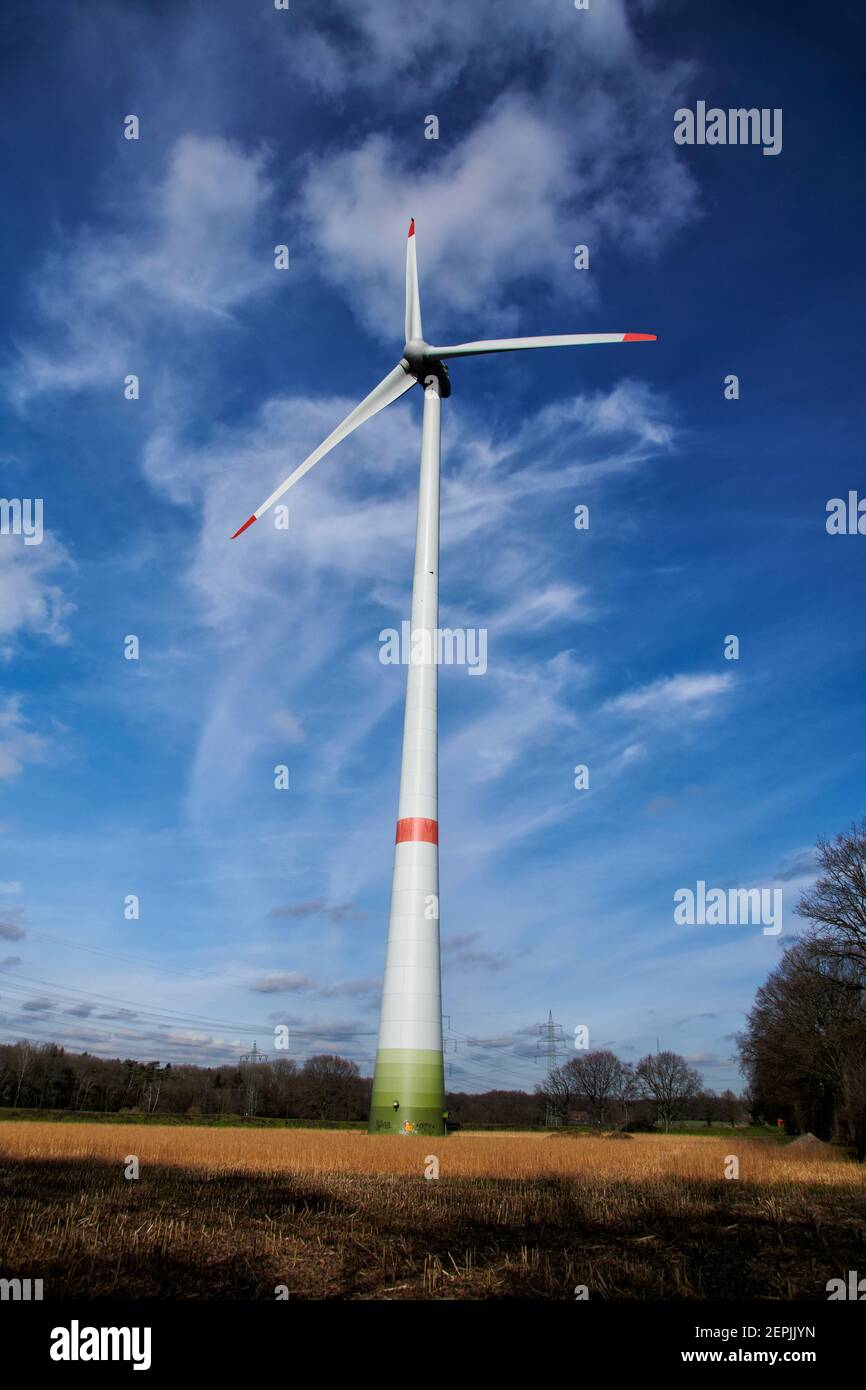 Windkraftanlage in einem Waldgebiet im Ruhrgebiet, Deutschland. Zusehen ist die ganze Windkraftanlage vor blauem Himmel mit einem schoenen Wolkenbild. Foto de stock