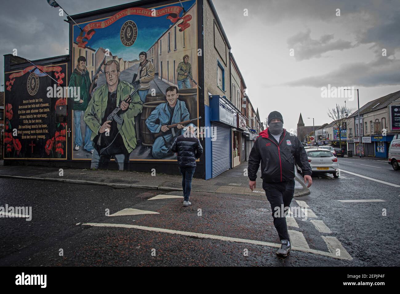 WEST BELFAST, IRLANDA DEL NORTE - West Belfast, Shankill Road - El hombre camina pasando Ulster Volunteer Force mural . Foto de stock