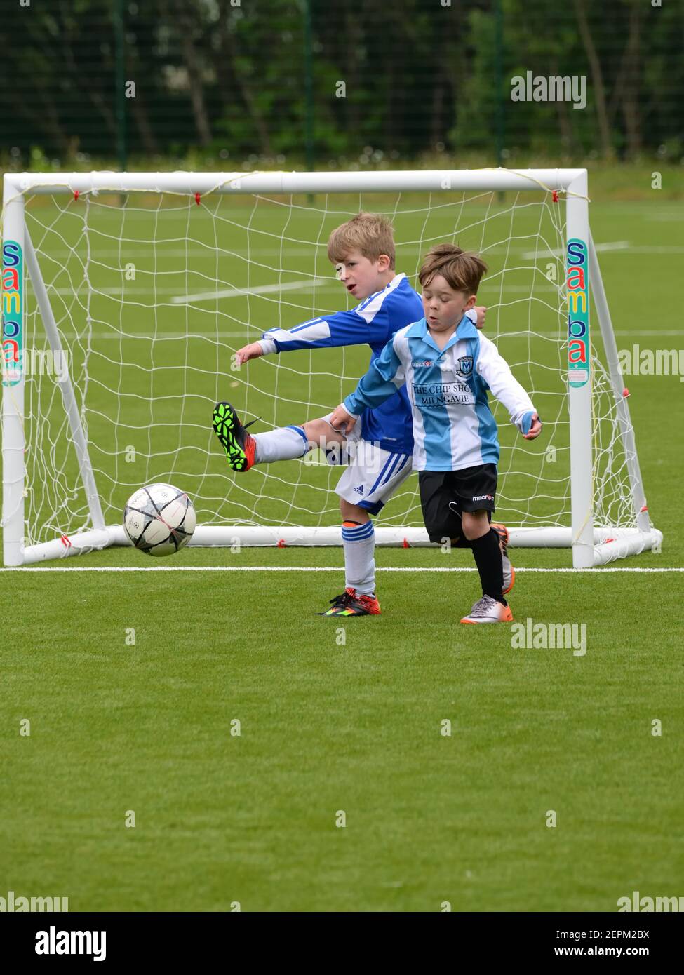 Dos niños pequeños juegan 7 un partido de fútbol organizado en una superficie artificial en Glasgow, Escocia, Reino Unido, Europa Foto de stock