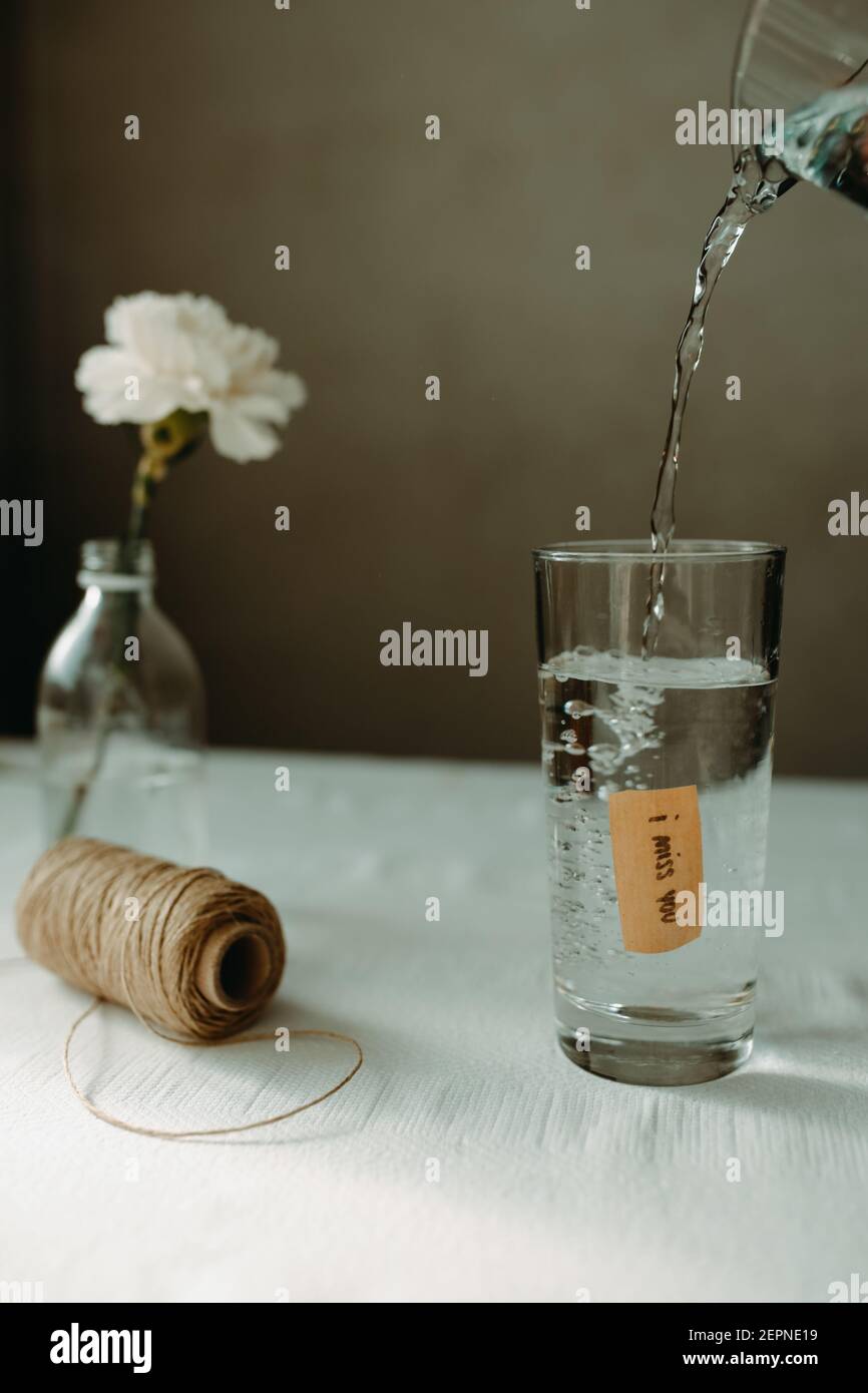 Agua vertiendo en cristalería con la inscripción que echo de menos que puso  cerca de madeja de hilo y encarnación floreciente Fotografía de stock -  Alamy