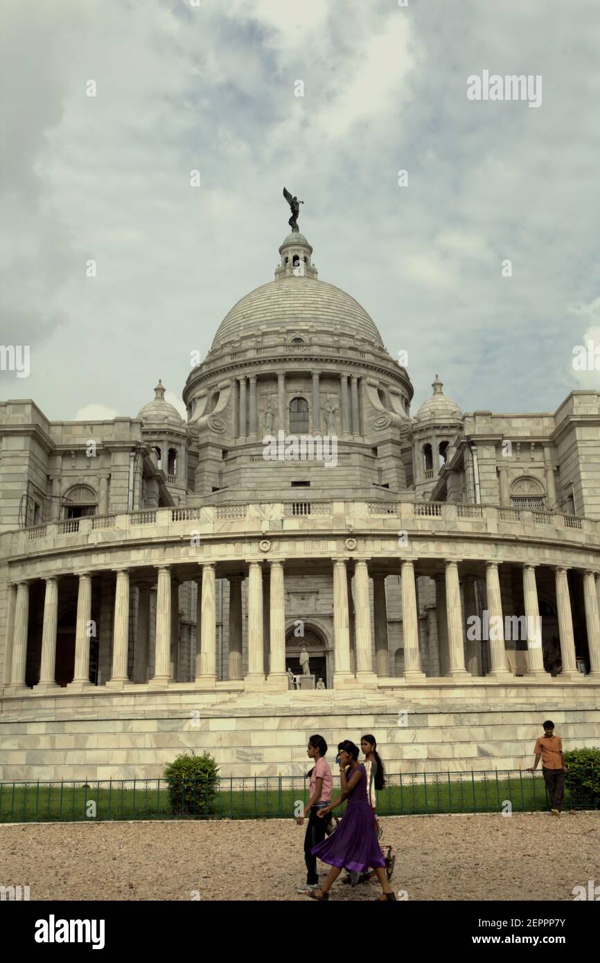 Los visitantes son fotografiados en un fondo de Victoria Memorial Hall en Kolkata, Bengala Occidental, India. En la parte superior de la cúpula central de la sala se encuentra una figura de Ángel de la Victoria, una diosa de la antigua mitología griega que personifica la victoria. Foto de stock
