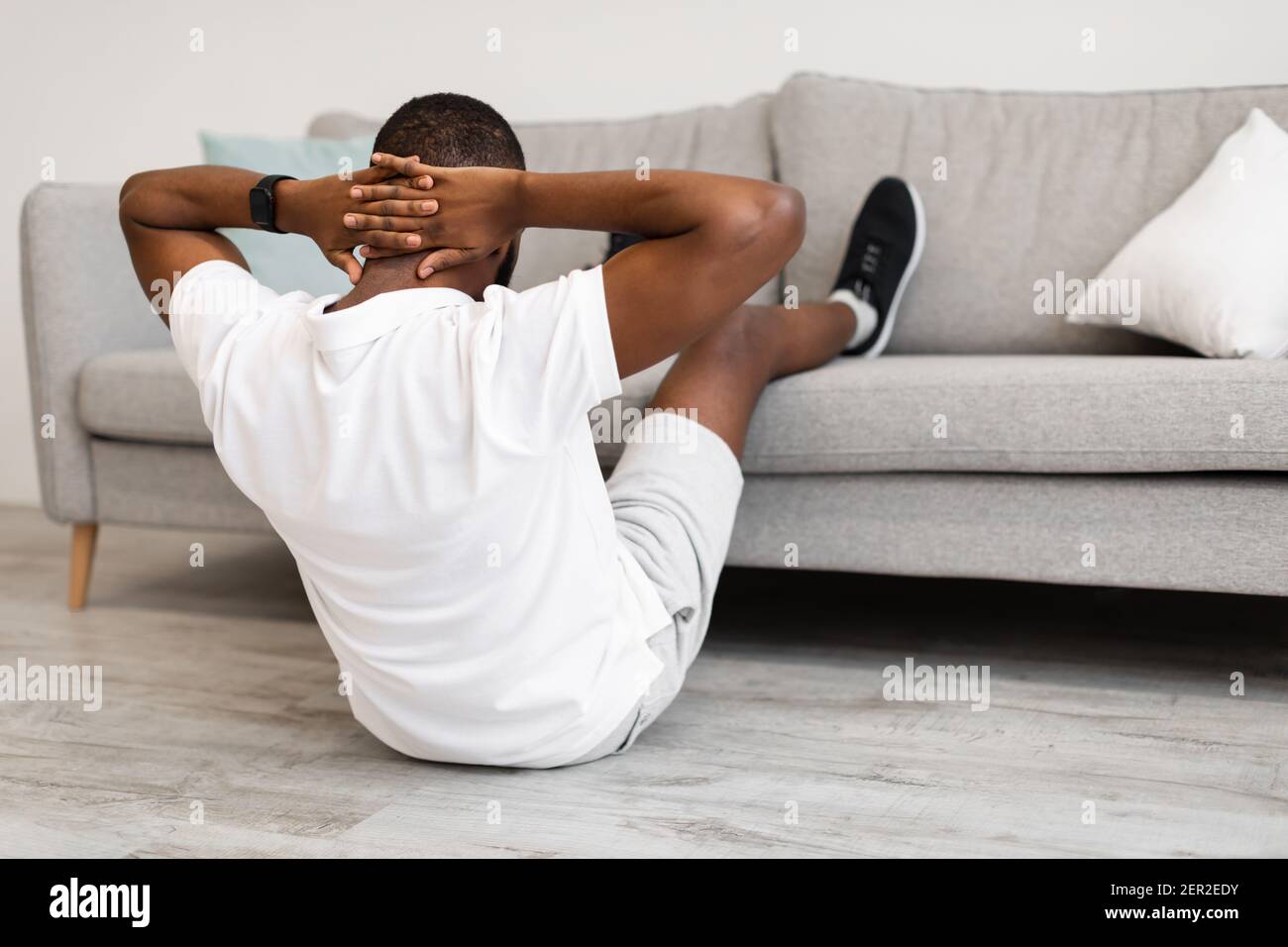 inalámbrico Murmullo electrodo Hombre haciendo abdominales con las piernas en el sofá ejercicio Interior,  Vista posterior Fotografía de stock - Alamy