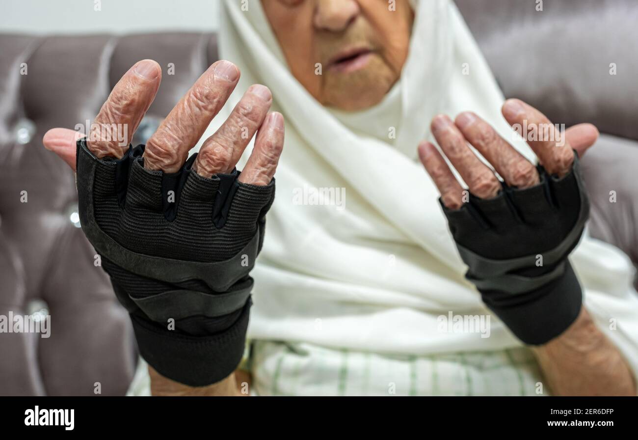 Mujer vieja usando guantes sin dedos para clima frío Fotografía de stock -