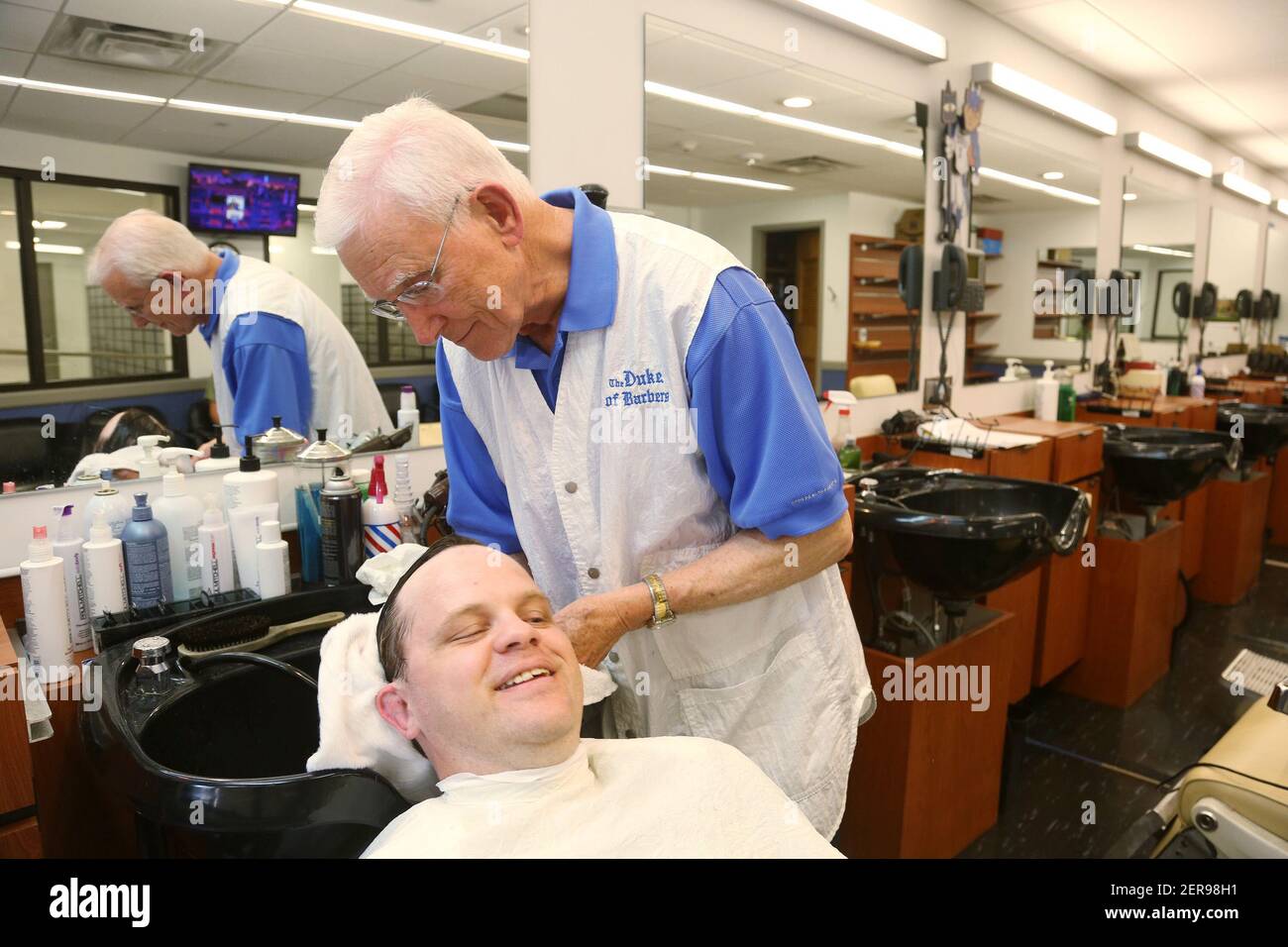 David Fowler, el barber principal en Duke Barbershop, lava el pelo de Adam Connor, cliente de larga data, el 25 de mayo de 2018. Fowler ha cortado el pelo allí por más de 50 años. Duke Barbershop cerrará a finales de mayo después de más de un siglo en el campus. (Foto de Juli Leonard/Raleigh News & Observer/TNS/Sipa USA) Foto de stock