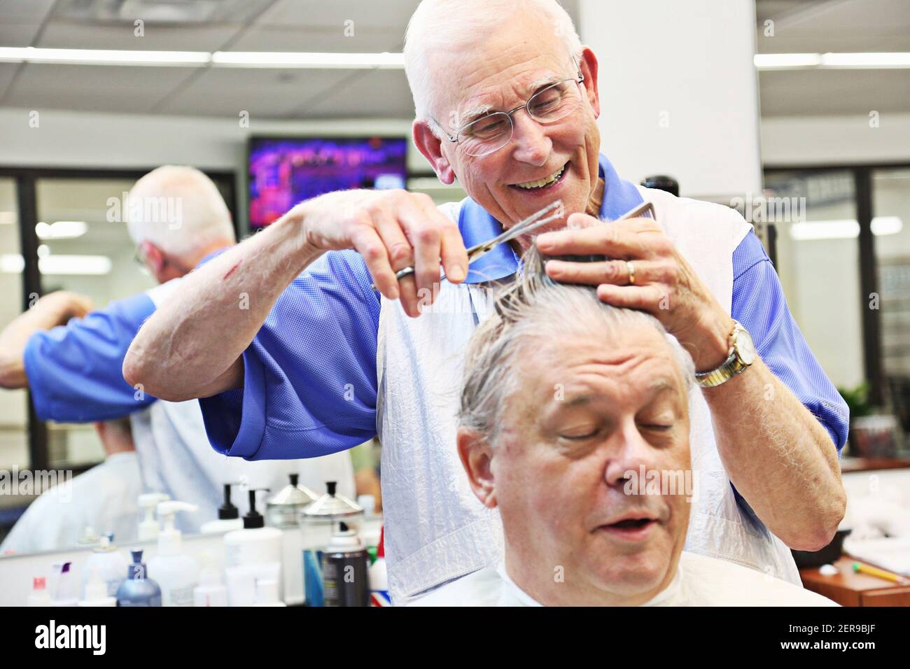 David Fowler, el barber principal en Duke Barbershop en Durham, N.C., se ríe con Jim Thames, el 25 de mayo de 2018. Duke Barbershop cerrará a finales de mayo después de más de un siglo en el campus, con Fowler cortando el pelo allí durante 55 años. (Foto de Juli Leonard/Raleigh News & Observer/TNS/Sipa USA) Foto de stock