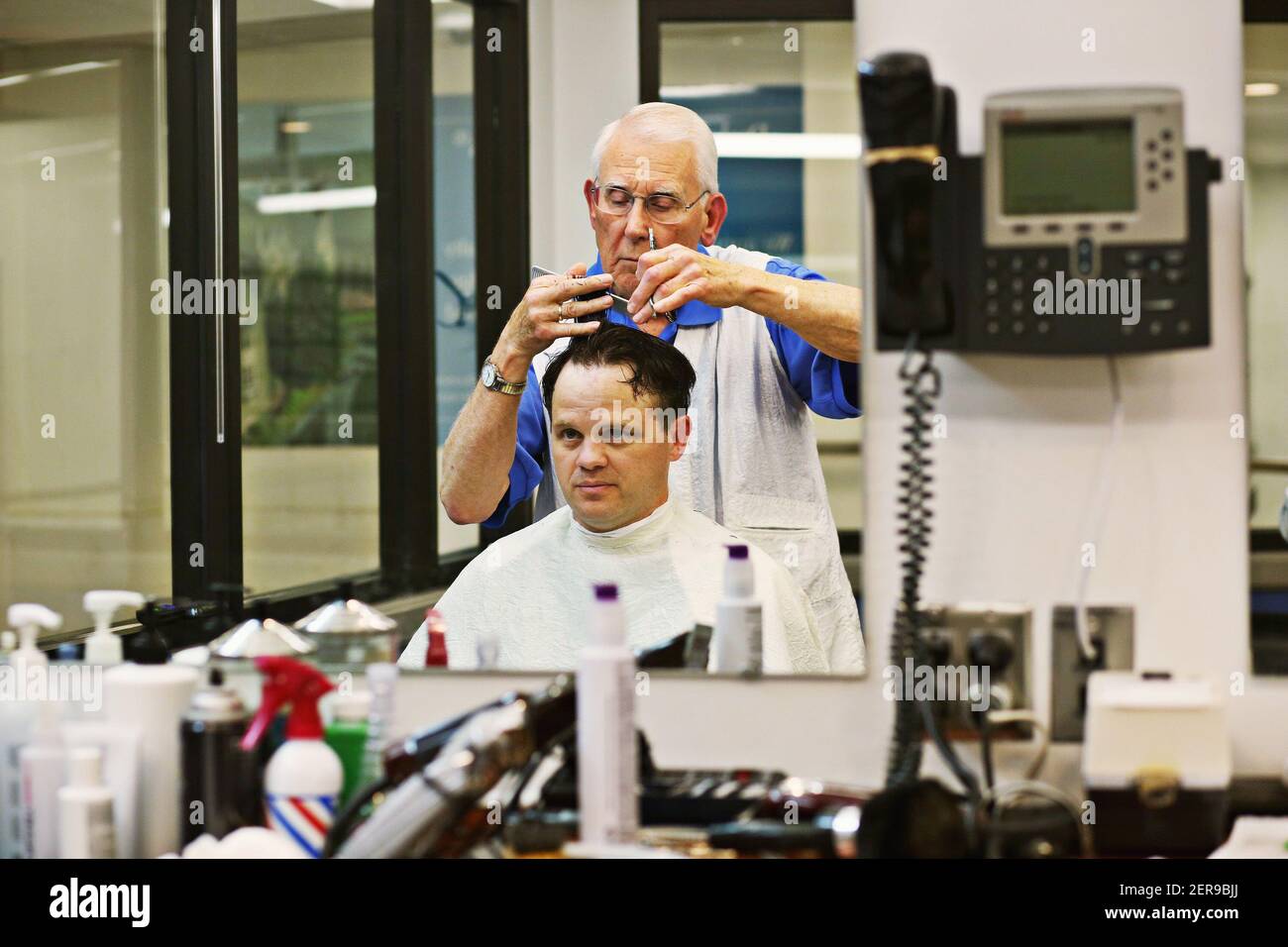 David Fowler, el barber principal en Duke Barbershop en Durham, N.C., corta el pelo del cliente de larga data Adam Connor el 25 de mayo de 2018. Duke Barbershop cerrará a finales de mayo después de más de un siglo en el campus, con Fowler cortando el pelo allí durante 55 años. (Foto de Juli Leonard/Raleigh News & Observer/TNS/Sipa USA) Foto de stock