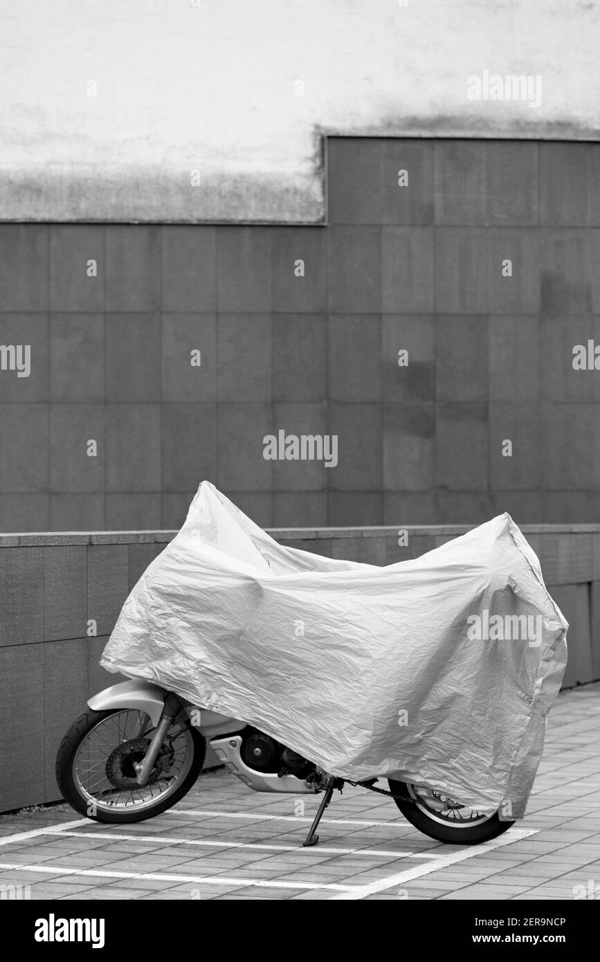 Motocicleta cubierta con una lona blanca Foto de stock