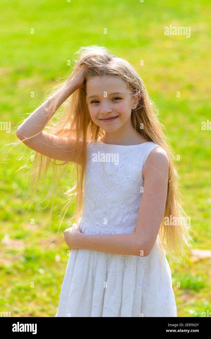 Hermosa niña de ojos azules con pelo largo rubio en un vestido blanco  caminando en el jardín de flores. Verano y primavera foto brillante y  emocional Fotografía de stock - Alamy