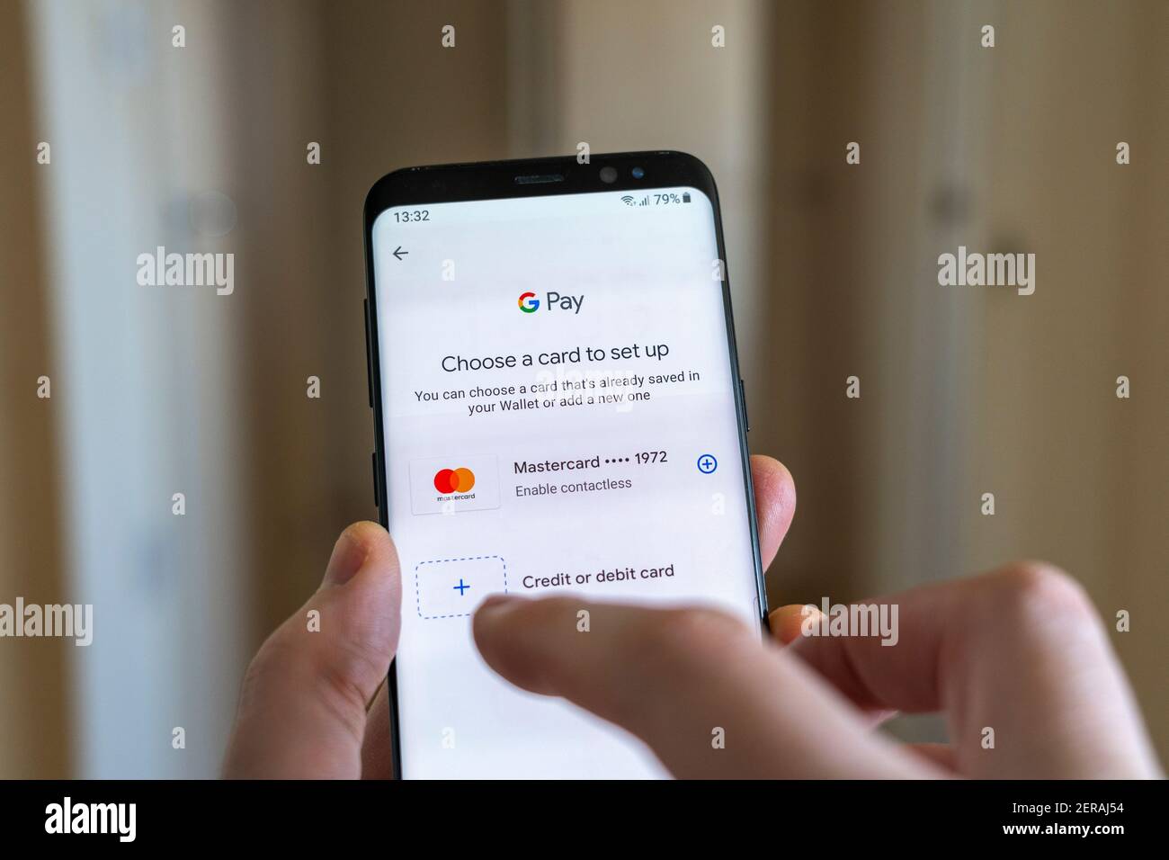 Un hombre que añade los datos de la tarjeta de pago a Google Pay aplicación en un smartphone que se sostiene en su mano Foto de stock