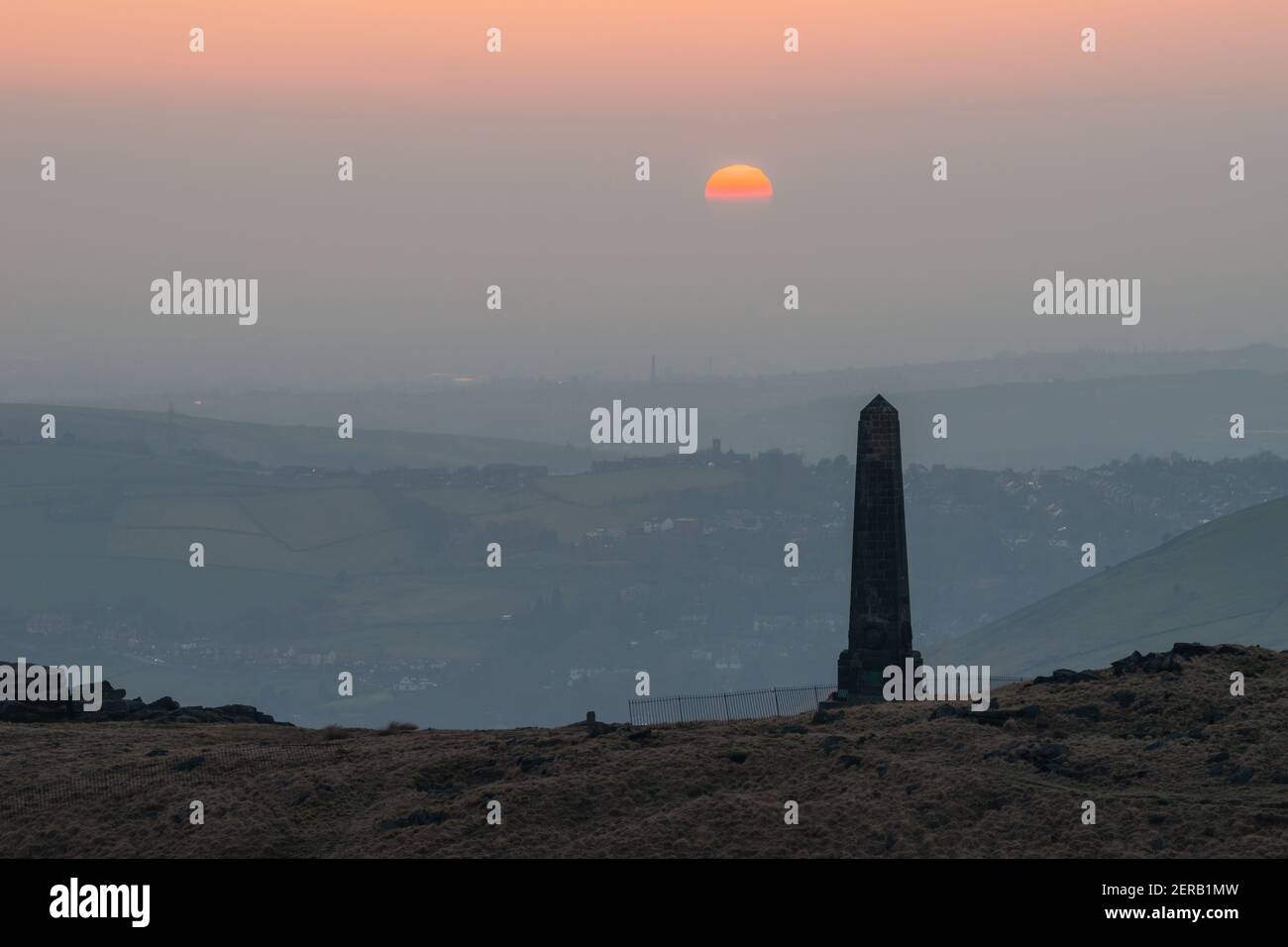 Puesta de sol sobre el obelisco del memorial de guerra en la colina de Alderman (también conocido como POTS y Pans) en Saddleworth, Inglaterra, Reino Unido Foto de stock