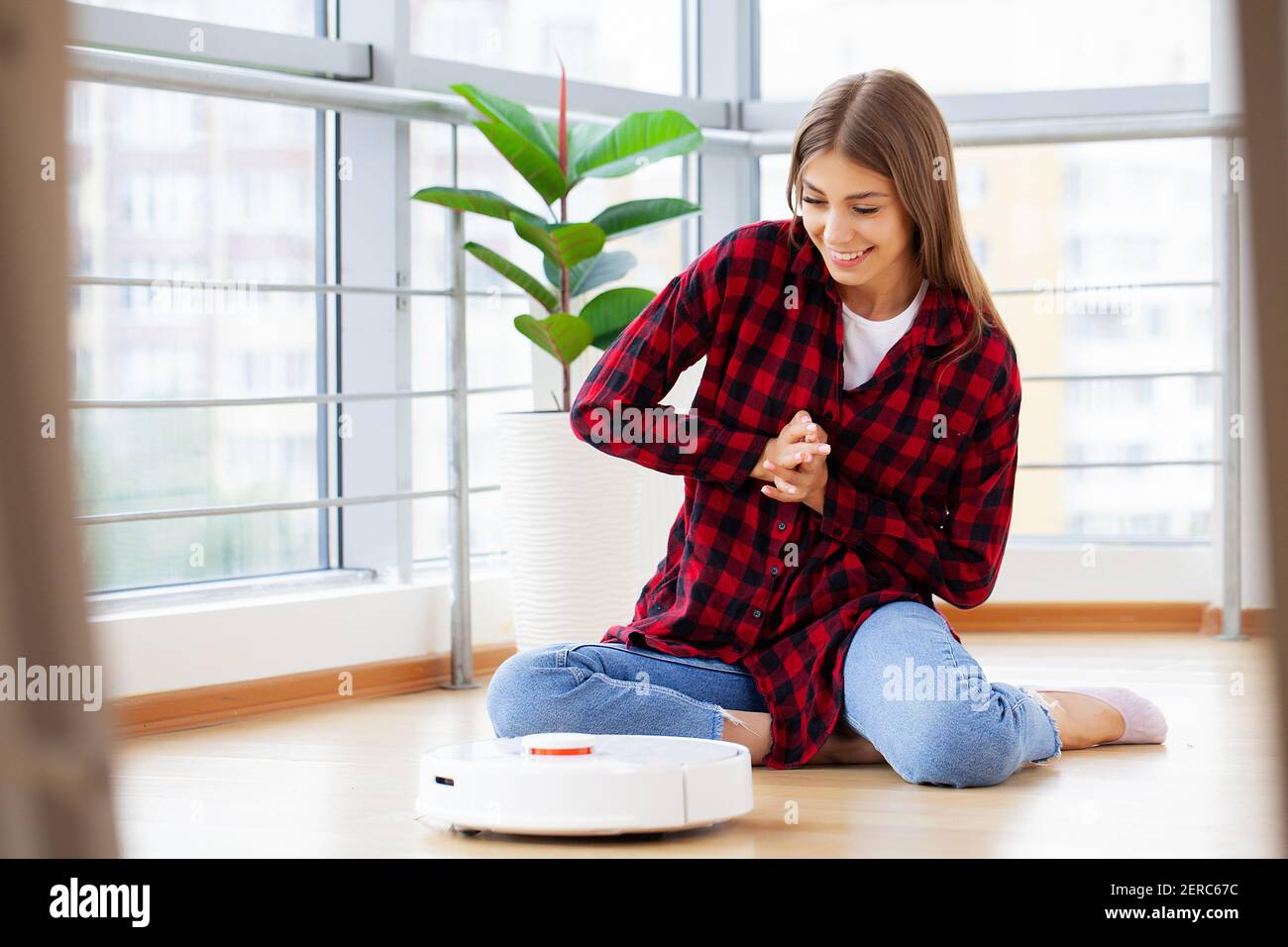 Mujer joven usando una aspiradora automática para limpiar el suelo,  controlando el robot de las máquinas domésticas Fotografía de stock - Alamy