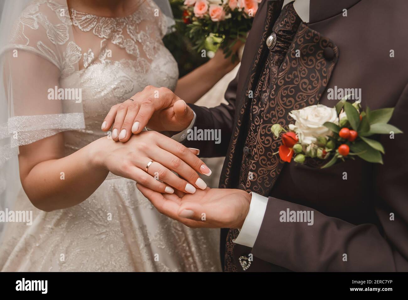 Las manos del novio en un golpe de traje marrón y acariciar las manos de la novia de cerca. Foto de stock