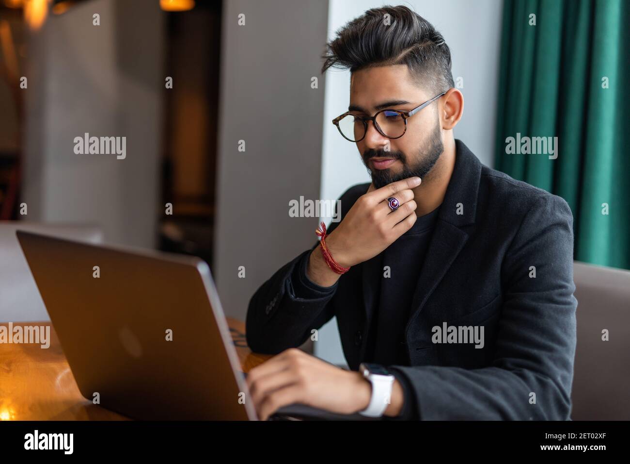Joven asiático trabajando con el ordenador portátil mientras bebía café en el espacio de trabajo. Foto de stock