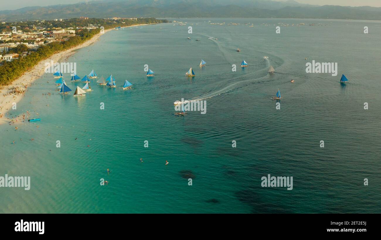 Vista aérea de los yates de vela en la playa de arena de la Isla Boracay en el ocaso del tiempo. Playa blanca tropical con velero. Concepto de vacaciones de verano y viajes. Foto de stock