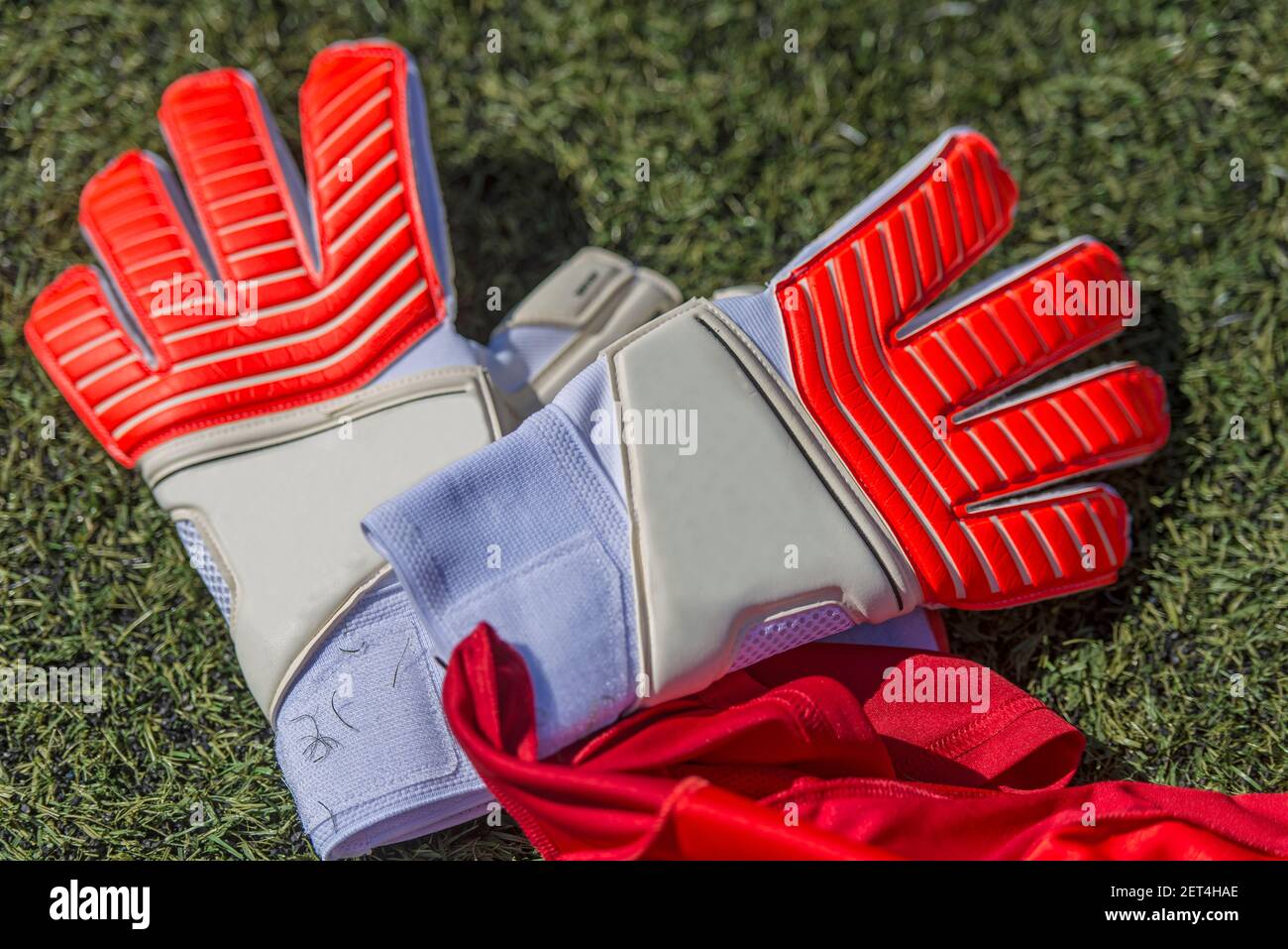Guantes de cuero para portero de fútbol, de color rojo y blanco, en el  campo de juego de césped artificial Fotografía de stock - Alamy