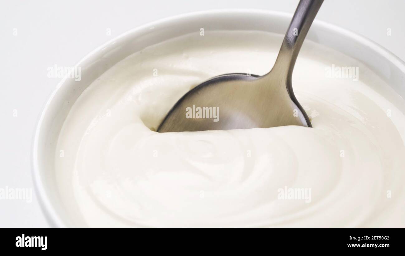 Plato de crema agria, yogur griego con cuchara Foto de stock