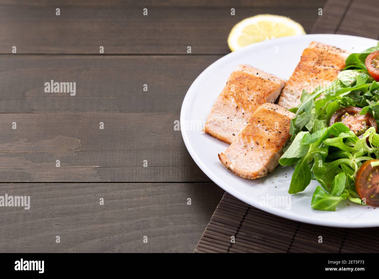 Filetes de salmón sobre plato blanco sobre mesa de madera oscura con copyspace. Foto de stock