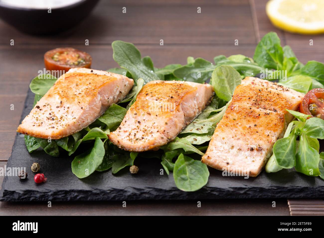 Filetes de salmón sobre pizarra sobre fondo de mesa de madera. Foto de stock