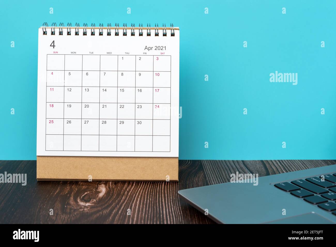 Calendario de escritorio 2021 de abril con ordenador portátil en la parte superior de la mesa Foto de stock