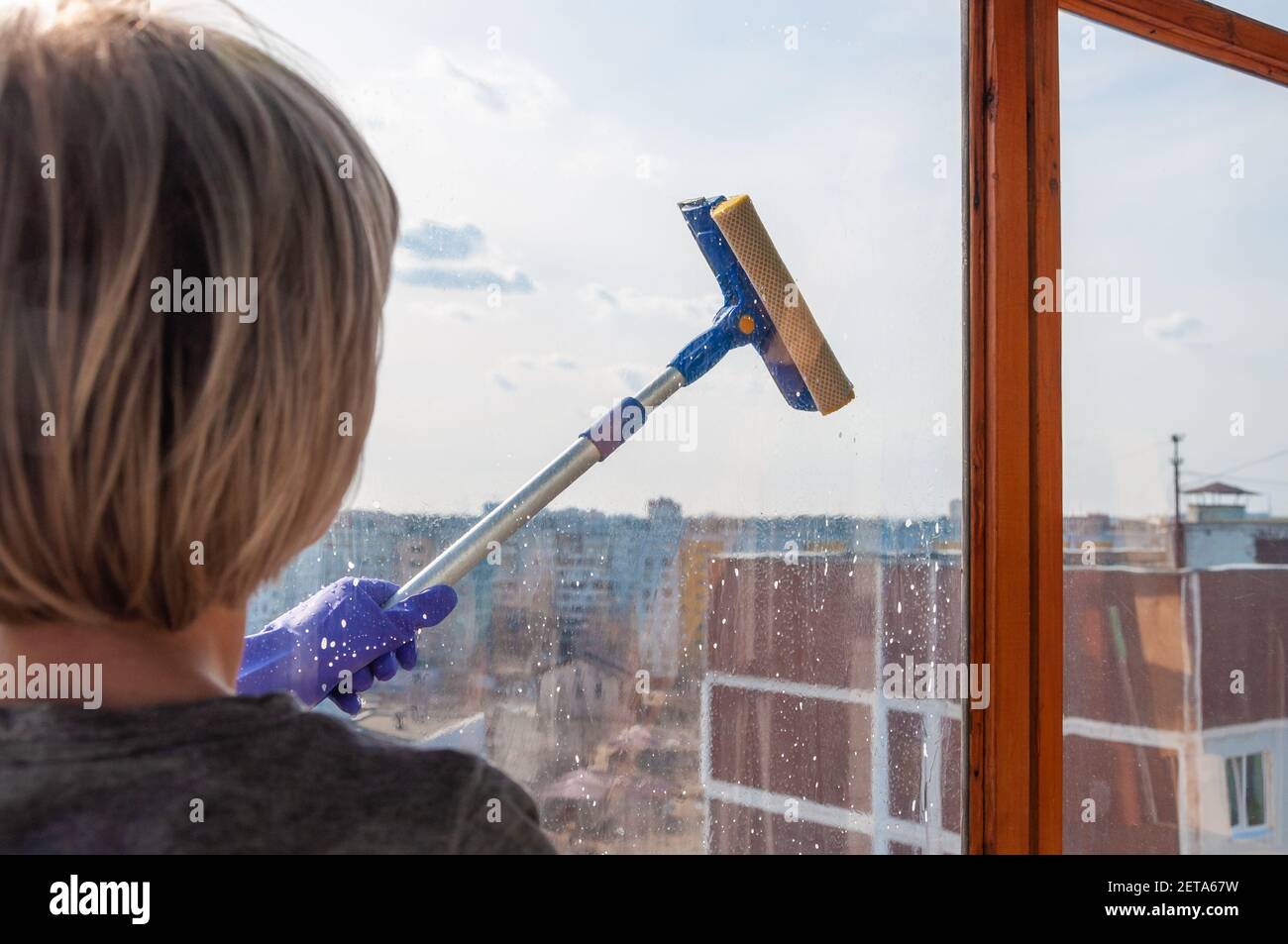 Un hombre limpia las ventanas de la casa. La mano con el guante de goma es  la celebración de la rasqueta para limpiar ventanas Fotografía de stock -  Alamy