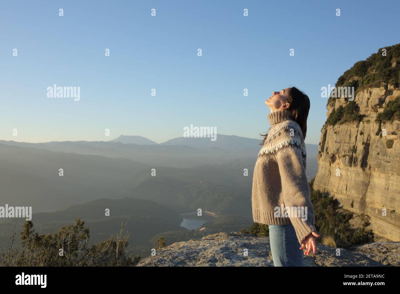 Vista lateral de una mujer en el suéter respirando aire fresco en la montaña en invierno Foto de stock