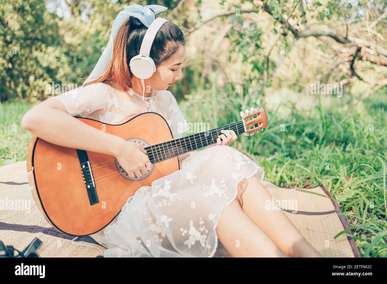 Chica con auriculares para escuchar música y tocar la guitarra en el  bosque. Pasatiempo musical y concepto de picnic Fotografía de stock - Alamy