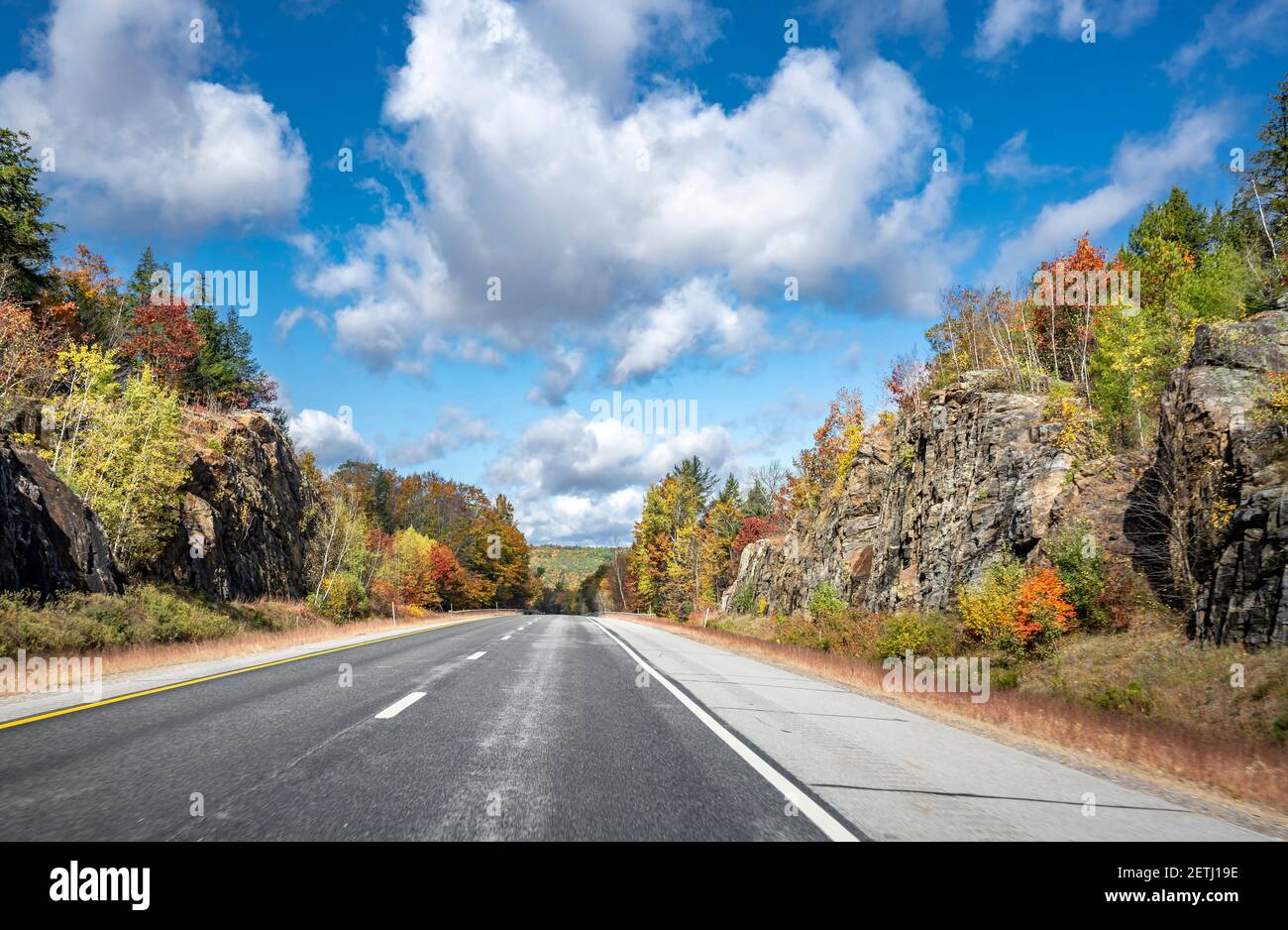 Fascinante y colorido carretera sinuosa de Nueva Hampshire bordeada de otoño arces árboles en rocas y acantilados invita al viajero en un una estancia inolvidable Foto de stock