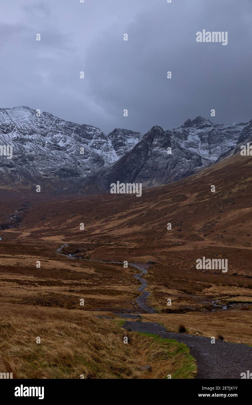 Largo camino con montañas nevadas, famoso lugar turístico, cielo nublado - piscinas de hadas - Isla Skye - Escocia - Reino Unido Foto de stock