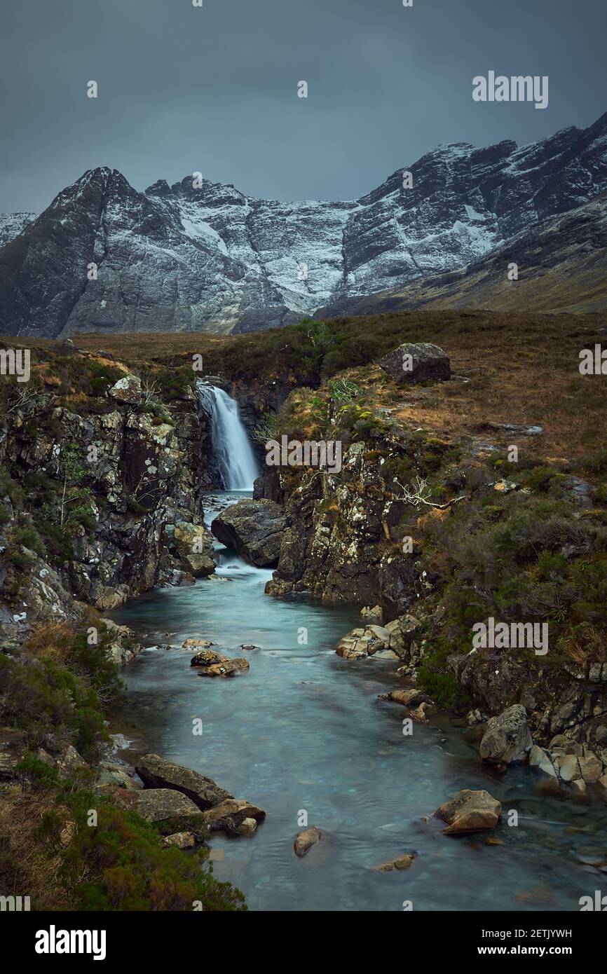 río con cascada en invierno, nieve y vegetación seca. Famoso destino turístico - piscinas de hadas - Isla Skye - Escocia - Reino Unido Foto de stock