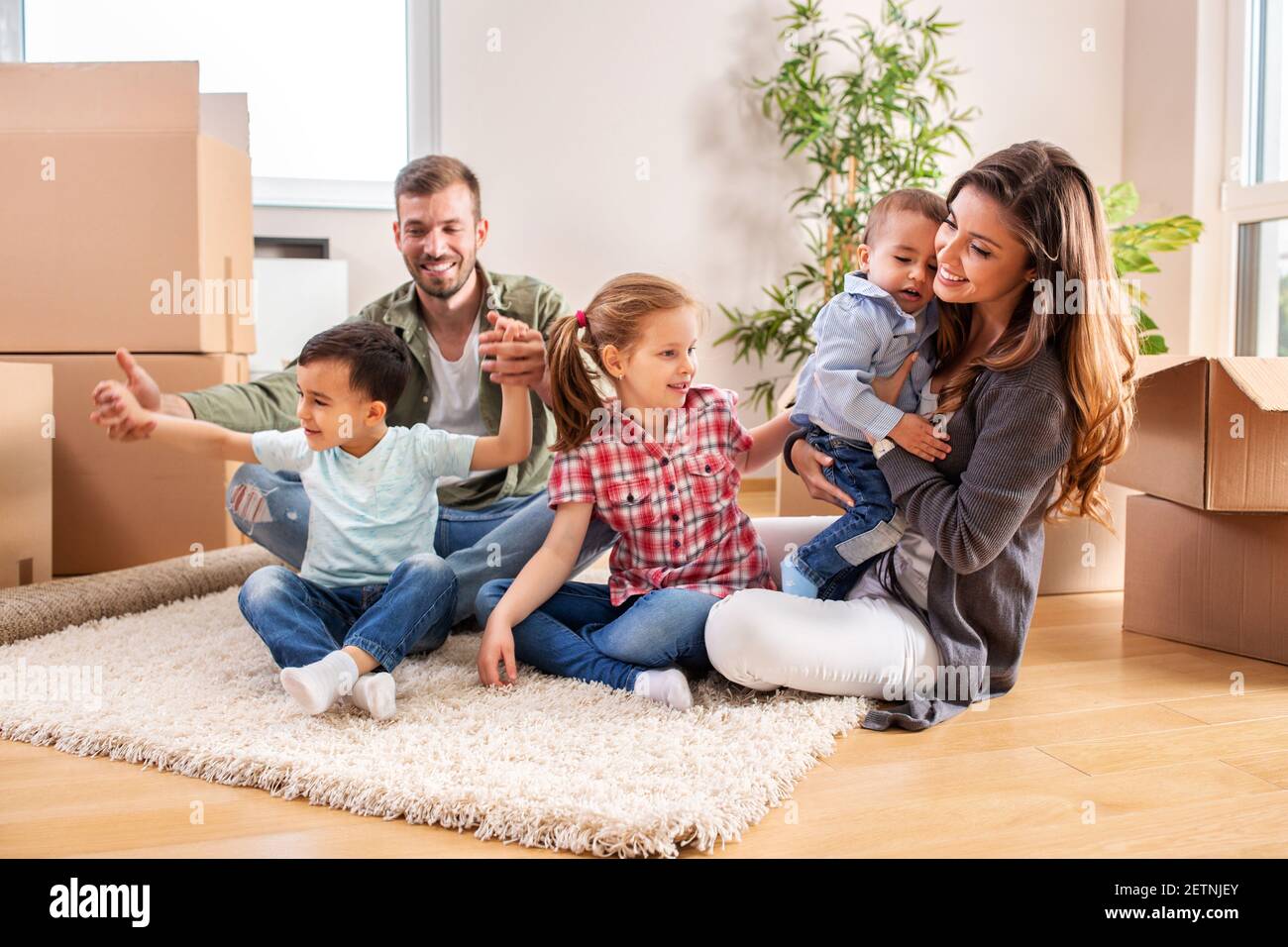 Recién se mudó en familia relajándose en casa nueva mientras hacía un descanso Foto de stock