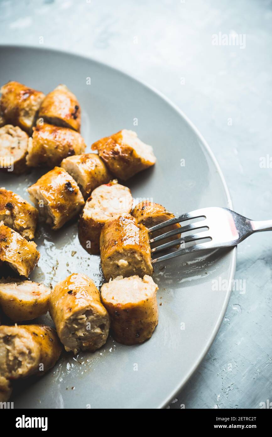 Salchichas a la parrilla en rodajas sobre plato con salsa clásica de mostaza. Enfoque selectivo. Profundidad de campo reducida. Foto de stock