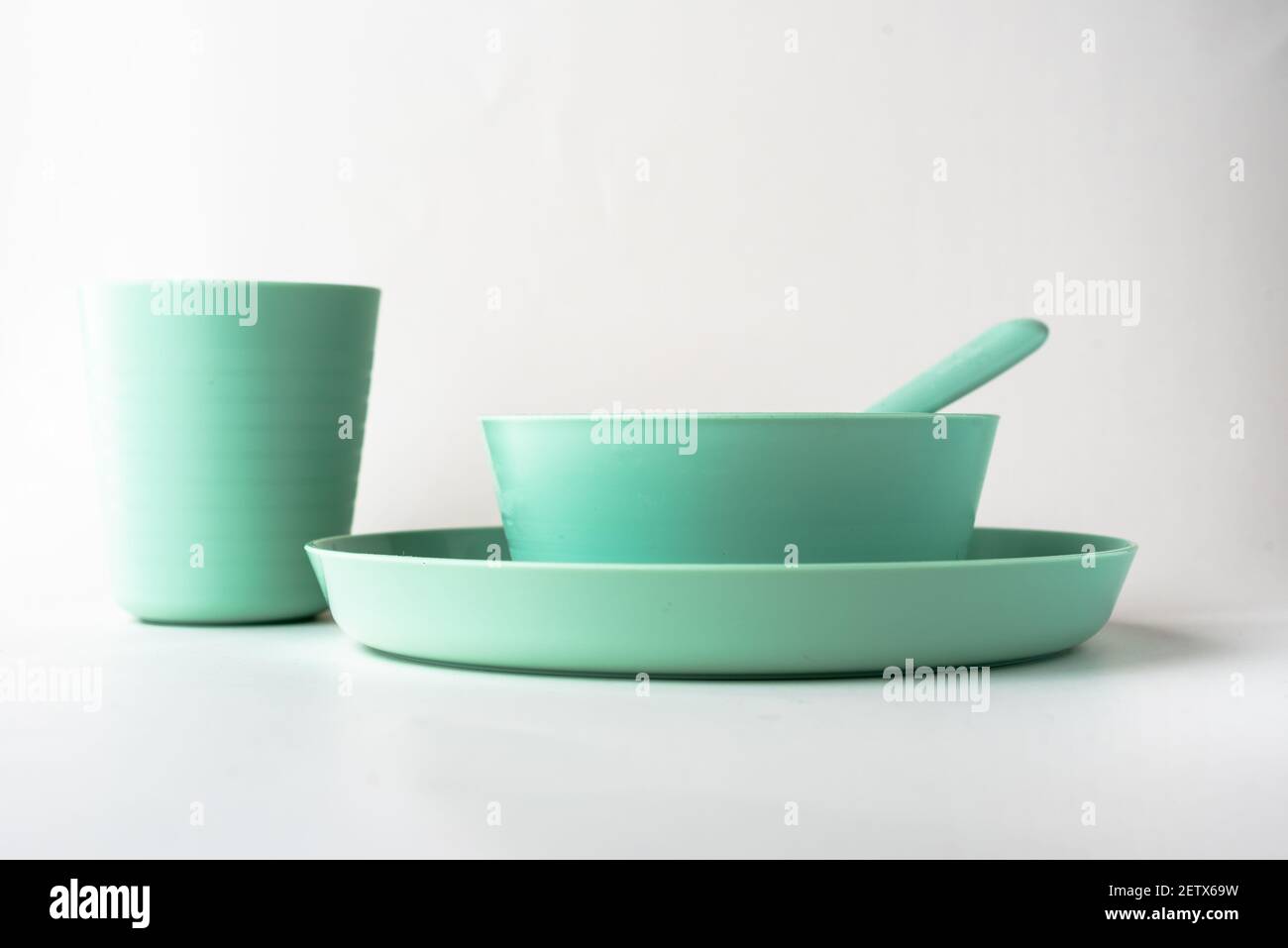 Vaso de plástico, plato y una cuchara aislados sobre fondo blanco, niños  verde cubiertos de plástico de colores Fotografía de stock - Alamy