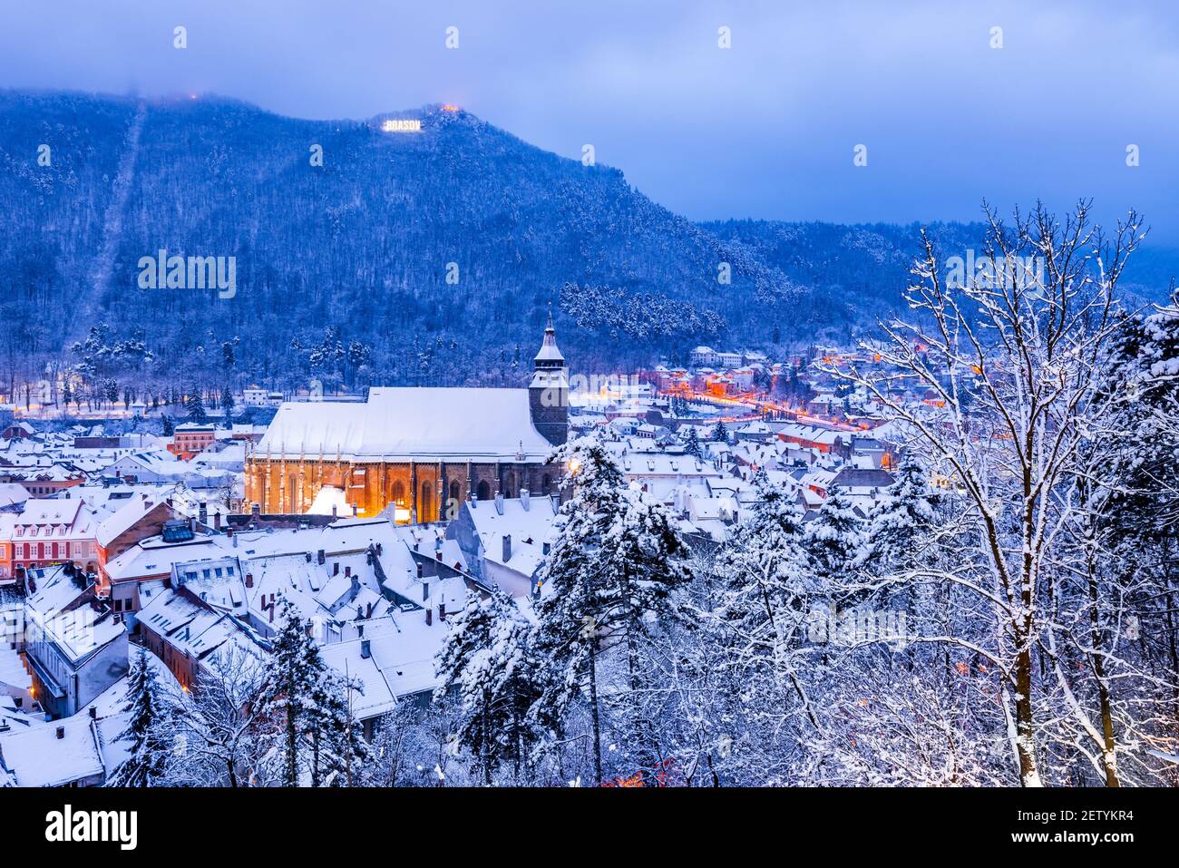 Brasov, Transilvania. Paisaje nocturno de invierno con la Iglesia Negra y las Montañas Cárpatos, viaje de invierno en Rumania. Foto de stock