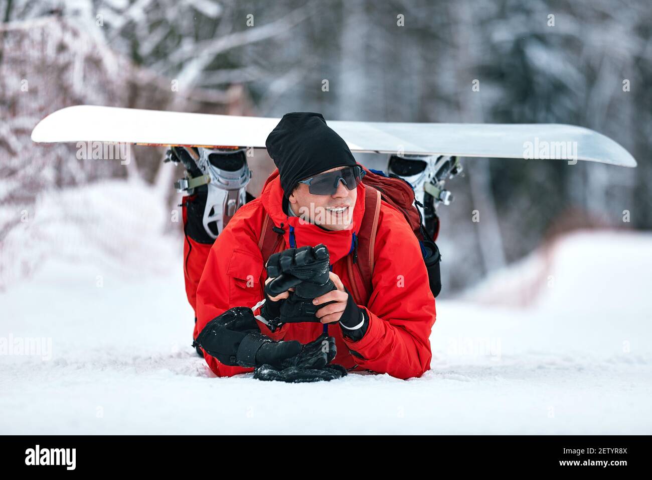 Hombre en traje de esquí rojo se sienta en la colina con su snowboard  Fotografía de stock - Alamy