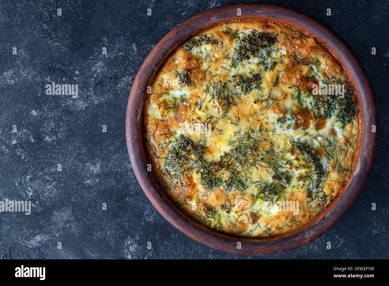 Cuenco de cerámica con frittata vegetal, comida vegetariana simple. Frittata con huevo, pimienta, cebolla, brócoli y queso sobre mesa de madera, primer plano. Italiano Foto de stock