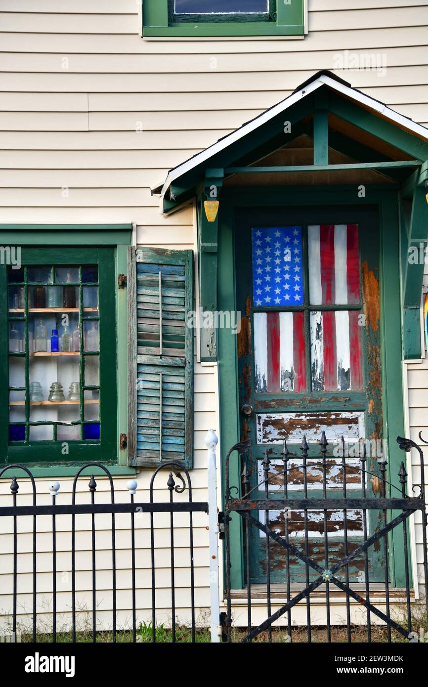 Una bandera americana hecha jirones cuelga dentro de una ventana de puerta Foto de stock