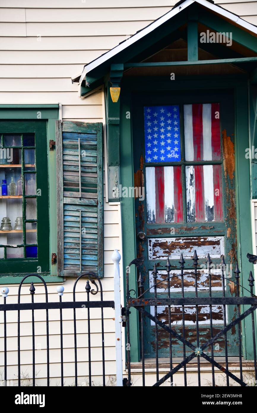 Una bandera americana hecha jirones cuelga dentro de una ventana de puerta Foto de stock