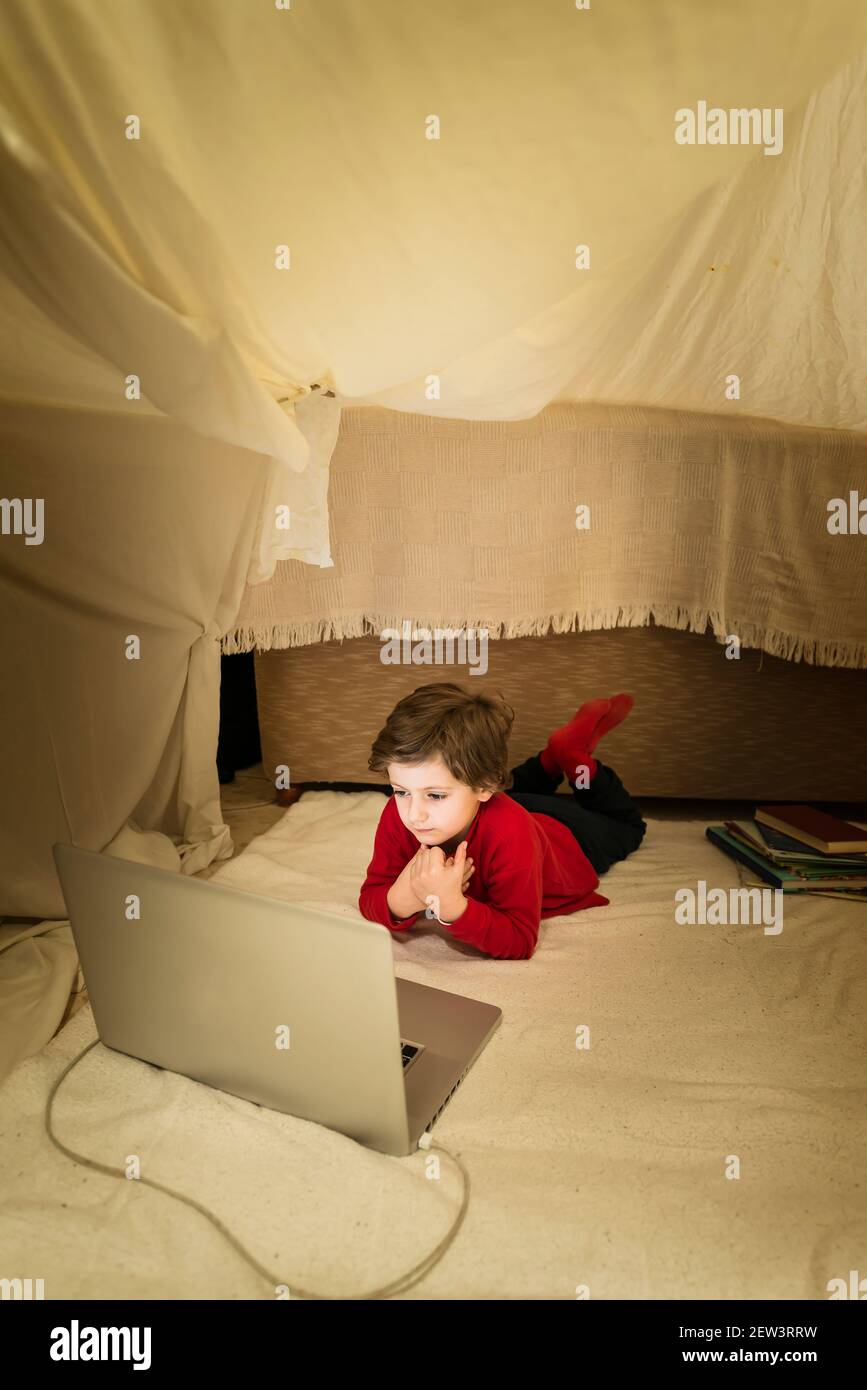 Un niño tumbado en una manta mirando un en una tienda improvisada su sala de estar. Concepto de estilo de vida en casa Fotografía de stock Alamy