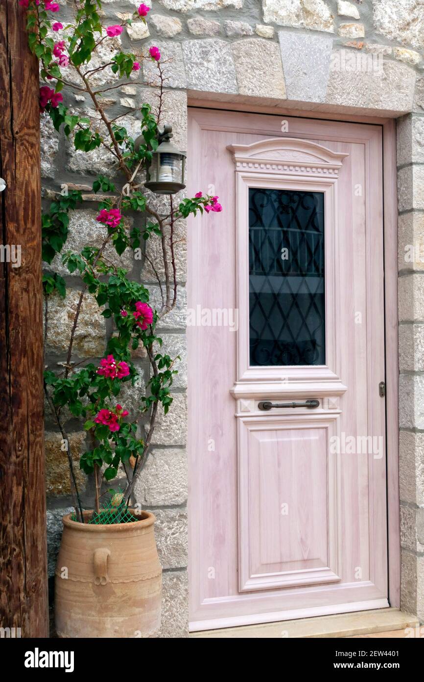 Puerta de estilo griego rosa con plantadora con flores rosadas n Ciudad vieja de Kefalos en la isla griega de Kos Foto de stock