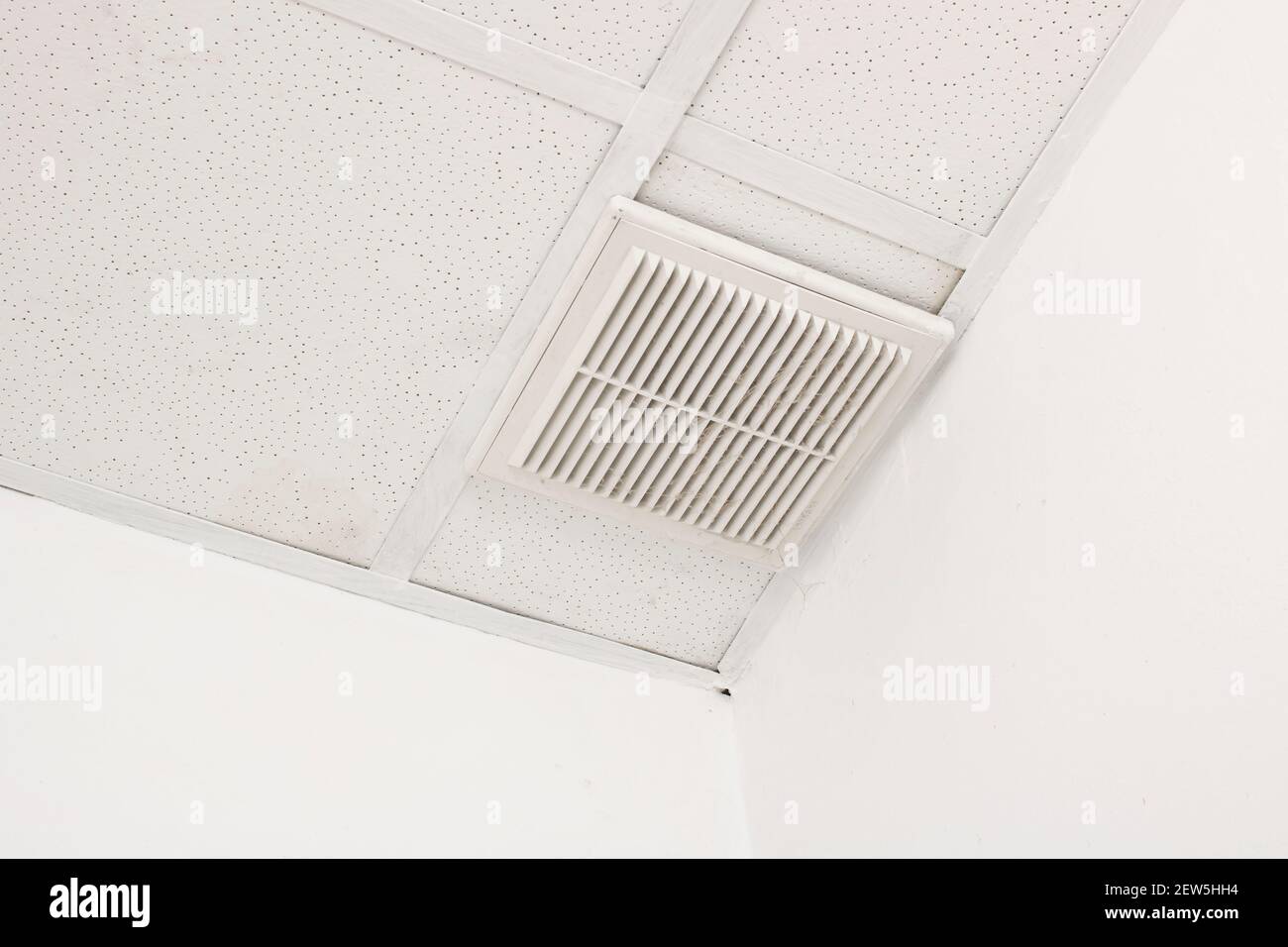 Rejilla de ventilación en un techo de baldosas blancas Foto de stock