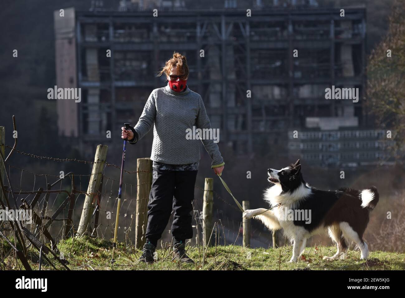 Buildwas, Shropshire, Reino Unido. 25 de febrero de 2021. Covid Fear Walker usando máscara facial. Una mujer caminando a su perro cerca de la desusada estación de energía de Buildwas Foto de stock