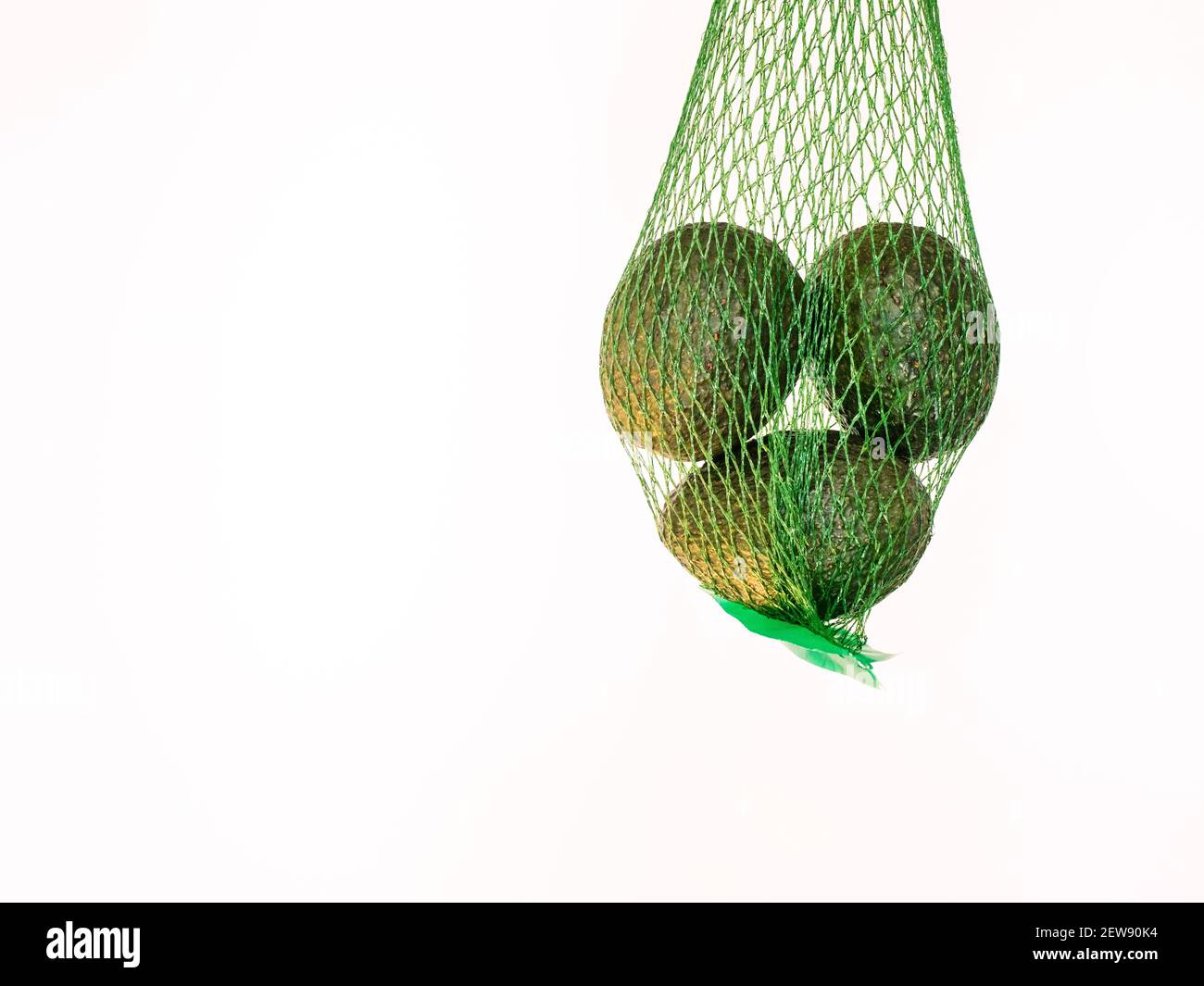 Aguacates en una red verde aislada y suspendida en el aire con un fondo blanco en el estudio Foto de stock